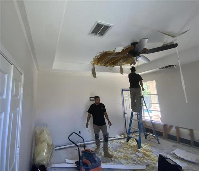 Bedroom with 2 technicians starting to remove collapsed ceiling