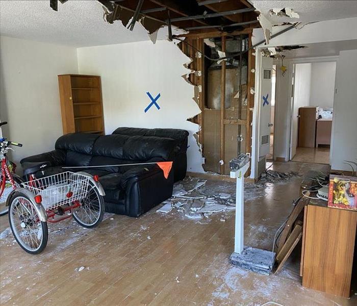 Living room showing furniture, wall and ceiling damaged by fire