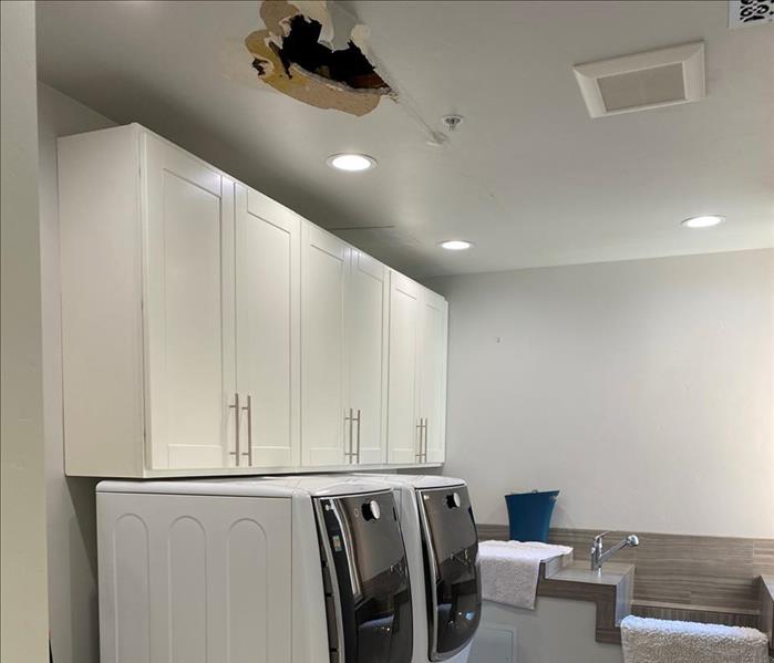 Laundry room with a hole in the ceiling