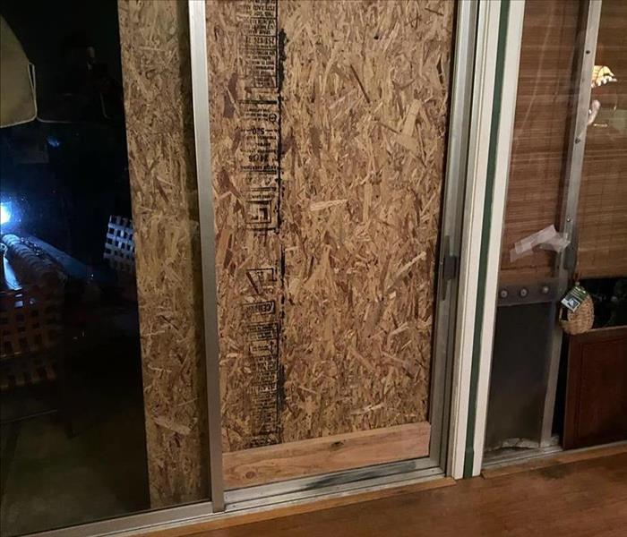 Broken sliding glass door boarded up with plywood