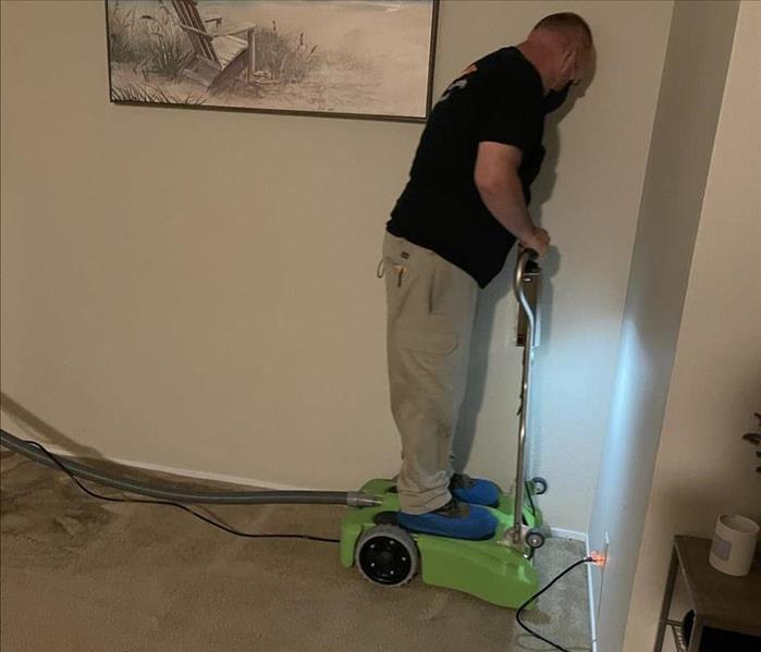 Project manager is using a water extraction machine to remove water from carpet